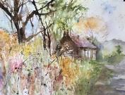 An English lane with banks of flowers and trees leading to a cottage